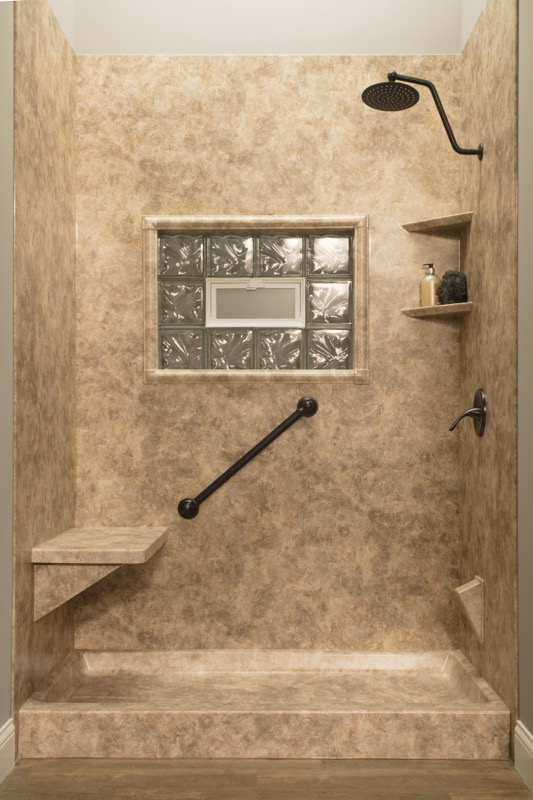 A low-step shower with a built-in corner bench, a grab bar and a handheld showerhead