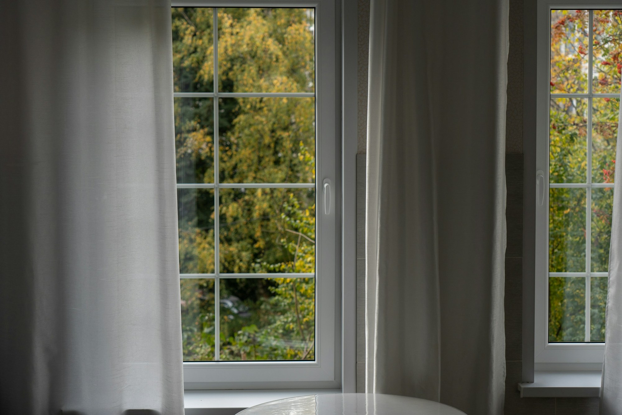 White-framed replacement windows in a bright residential room, shown for illustration
